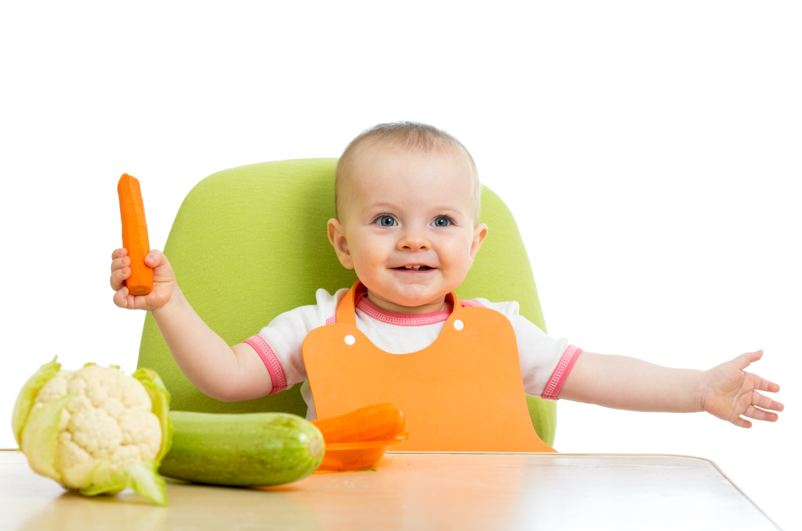 baby sitting at a green highchair eating vegetables